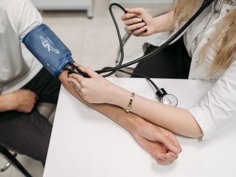 A doctor measures a patient's blood pressure with a sphygmomanometer during a consultation.